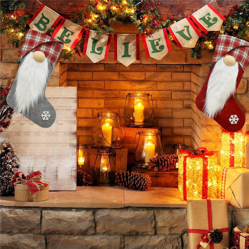 ELITE CASA Christmas stockings hanging by the fireplace with festive decorations and glowing candles.